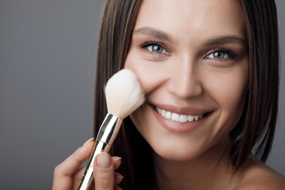 Modelo aplicándose maquillaje con brocha